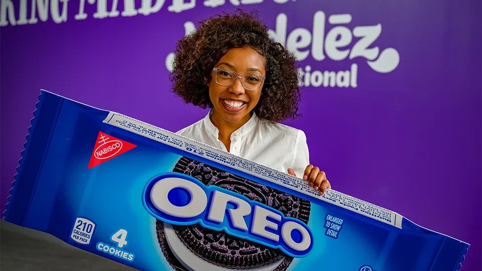 women smiling holding an oversized box of oreos